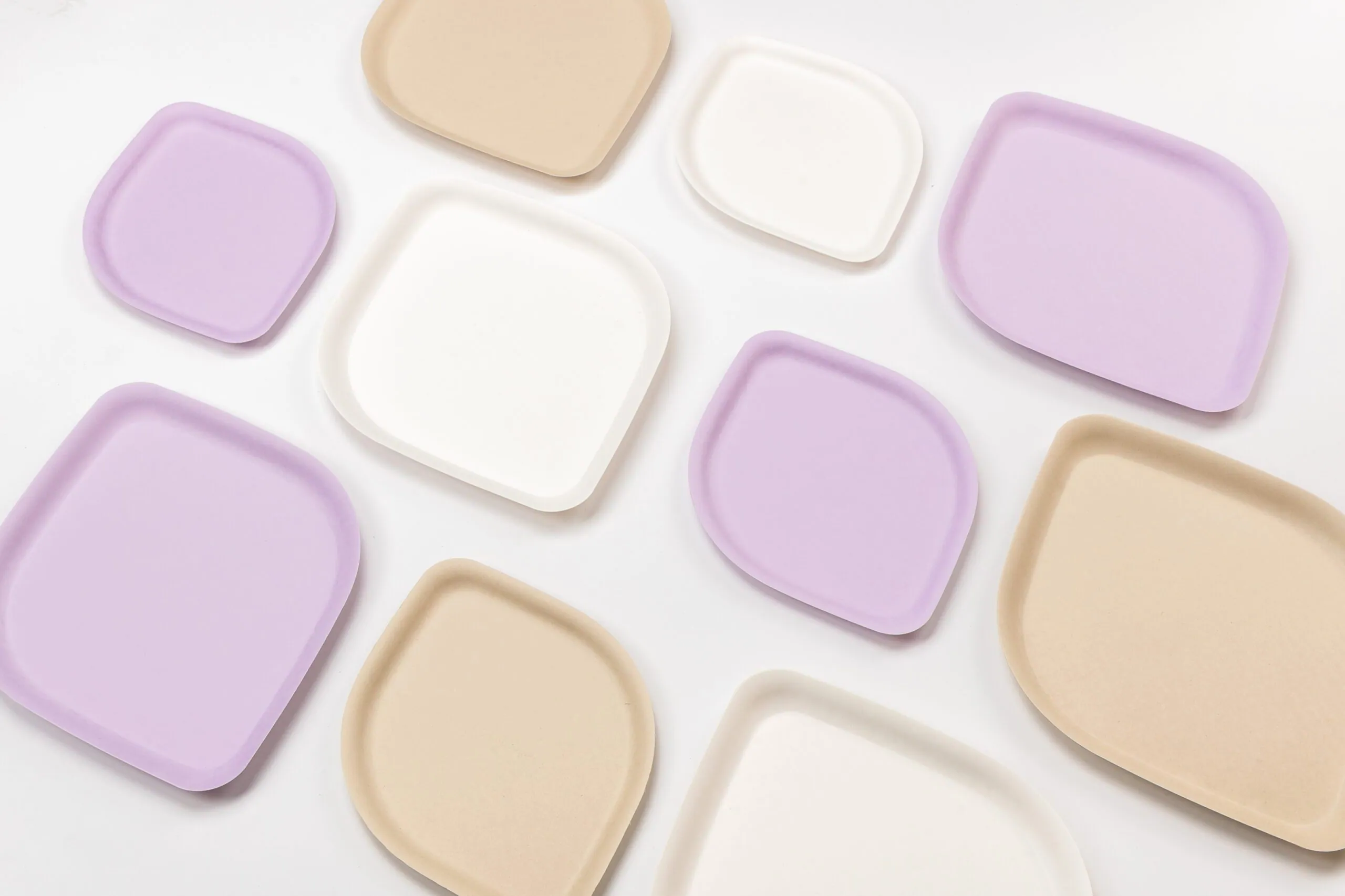 Square and rounded plates in pastel shades are artfully arranged on white for a serene aesthetic.